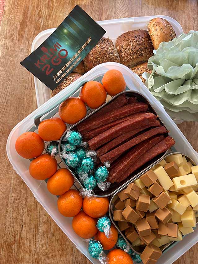 bunte Brotboxen mit Brötchen, Wurst, Käse und Tomaten